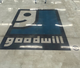 Lights reflect off of the Goodwill floor logo