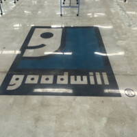 Lights reflect off of the Goodwill floor logo