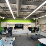 A photo of a classroom interior with bright green walls and gray track lighting on the ceiling