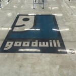 a photo of lights reflecting on the goodwill logo on a shiny floor