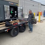 A photo of workers standing next to a generator on a trailer