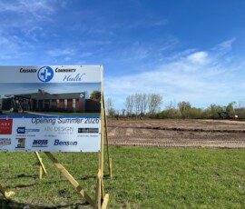 Construction sign for Crusader Community Health showing a rendering of the future building and text reading “Opening Summer 2026,” with project partners and contractors listed.