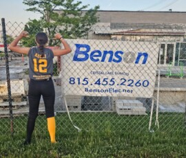 A softball player in front of a Benson construction sign